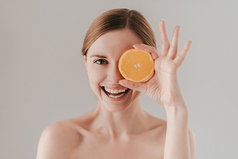 Mulher sorrindo segurando uma laranja